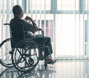 Elderly man in wheelchair looking outside of window