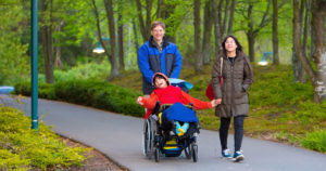 Child in wheelchair happy outside with family in park