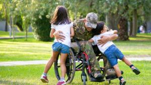 Veteran in wheelchair outside hugging children